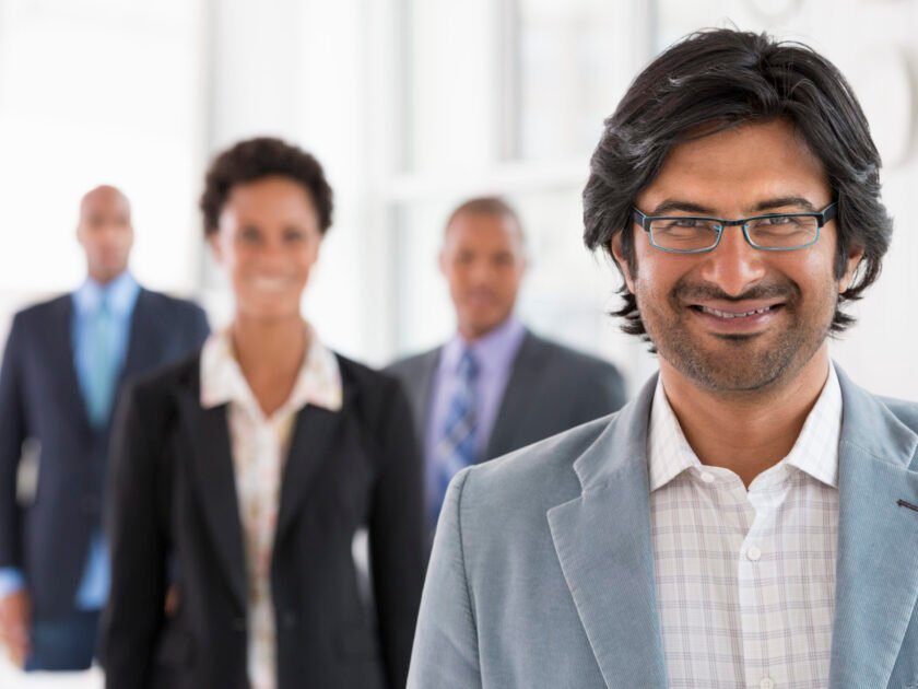 A business environment, a light airy city office. Business people. A team of people, a department or company. Three men and one woman.