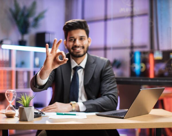 Focus on sign ok, okay. Close up portrait of indian financial expert office worker sitting at table