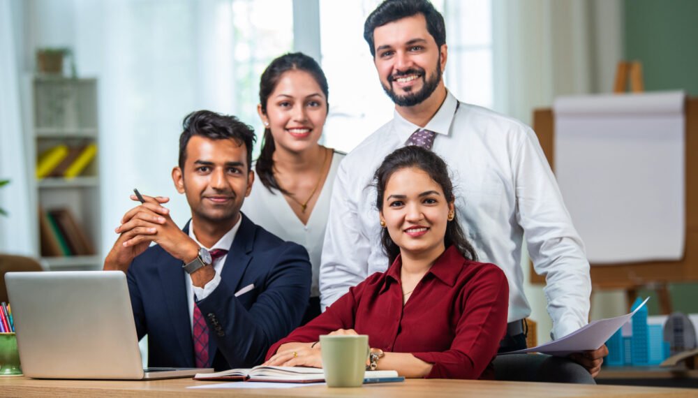 Indian asian young business professionals using laptop on desk discussing strategy