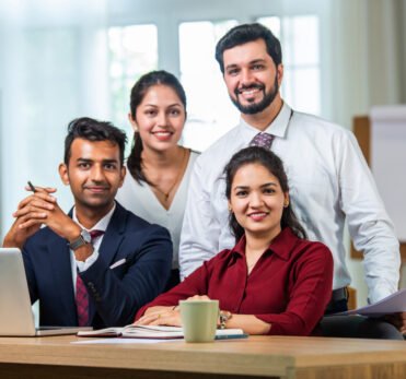 Indian asian young business professionals using laptop on desk discussing strategy