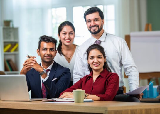 Indian asian young business professionals using laptop on desk discussing strategy