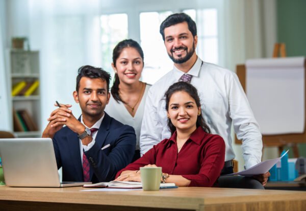 Indian asian young business professionals using laptop on desk discussing strategy