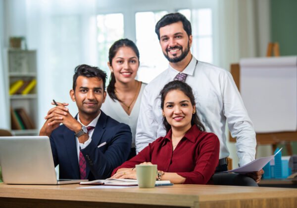Indian asian young business professionals using laptop on desk discussing strategy