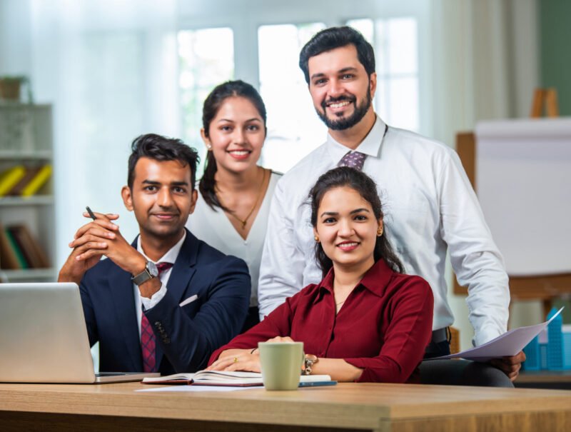 Indian asian young business professionals using laptop on desk discussing strategy