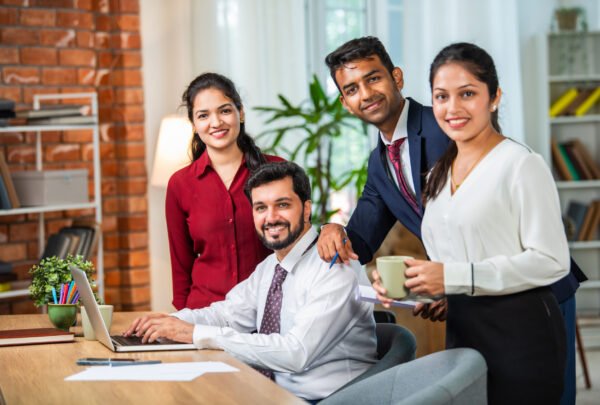 Indian asian young business professionals using laptop on desk discussing strategy