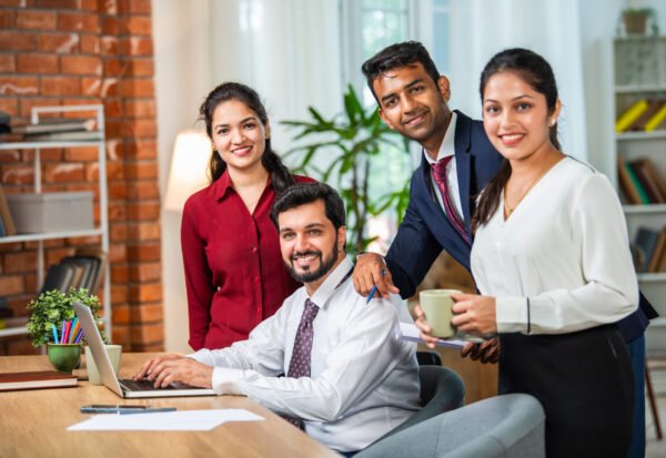 Indian asian young business professionals using laptop on desk discussing strategy