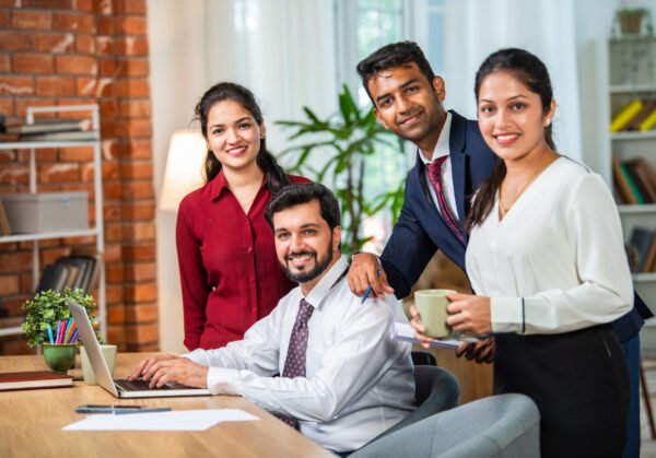 Indian asian young business professionals using laptop on desk discussing strategy