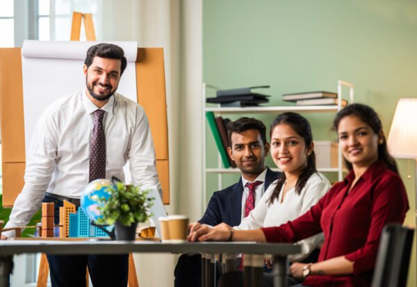 Indian asian young business professionals using laptop on desk discussing strategy