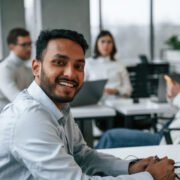 Man is sitting in front of his colleagues. Four people are working in the office together.