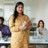 Portrait of mature smiling businesswoman filling from on clipboard